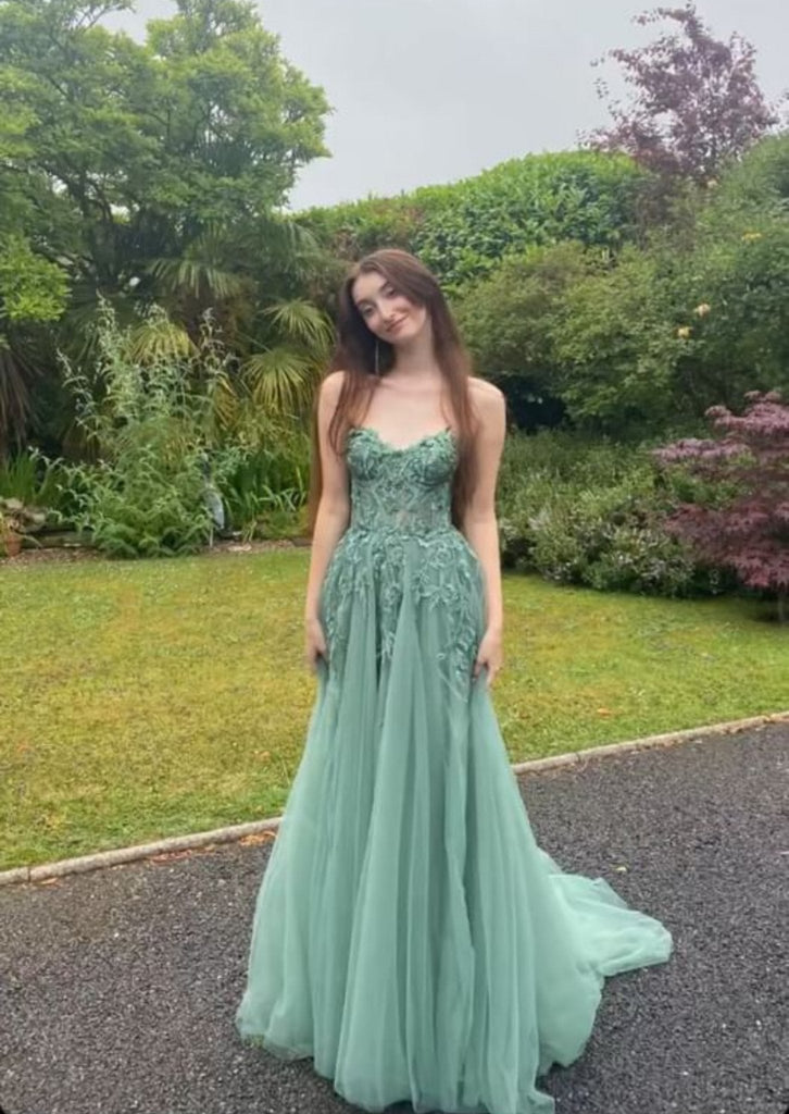 Elegant green corset top tulle dress with floral embroidery, ideal for prom or bridesmaid wear, showcased in a garden setting.