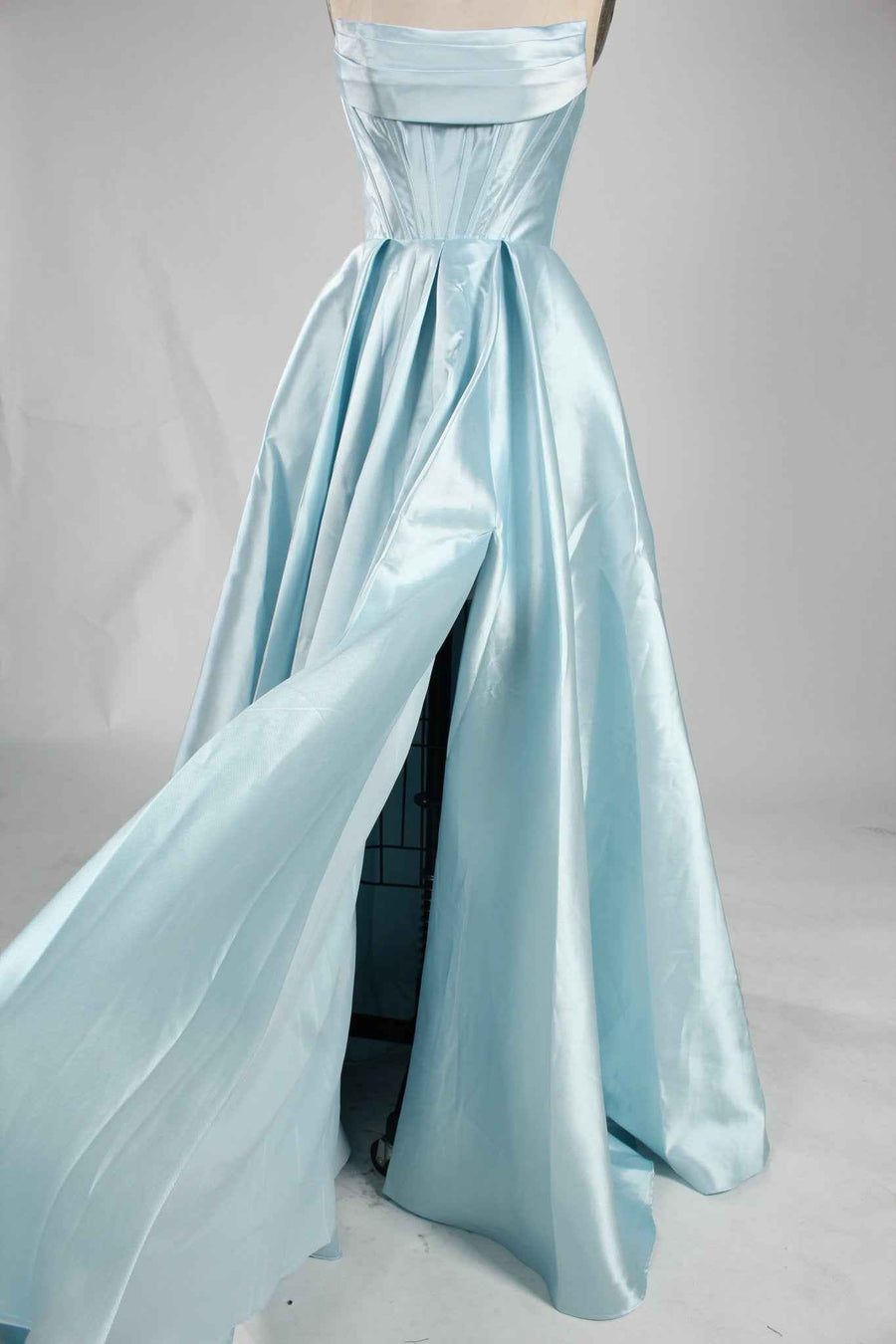 Carmen Ball Gown in light blue satin with strapless neckline, pleated skirt, and dramatic side split. Elegant formal dress with hidden pockets.