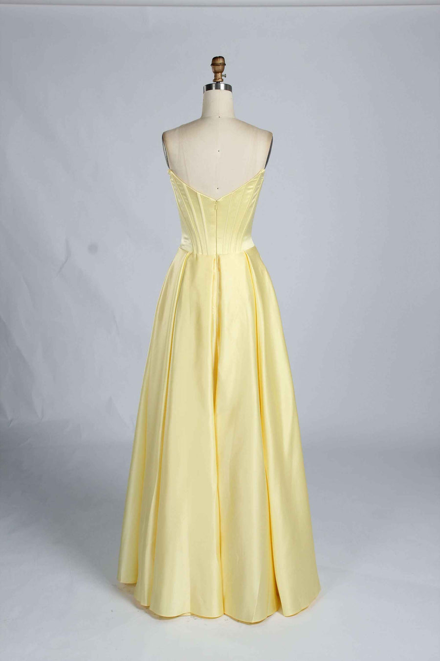 Back view of light yellow Jessica Stuart Darcet Prom Gown with V-back corset and flowing satin skirt.
