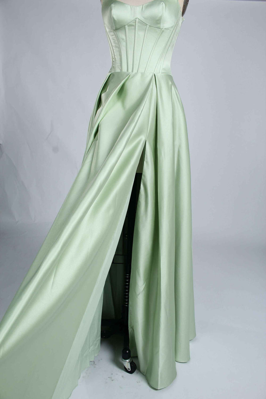 Side view of sage green Jessica Stuart Darcet Prom Gown highlighting thigh-high slit and elegant satin drape.