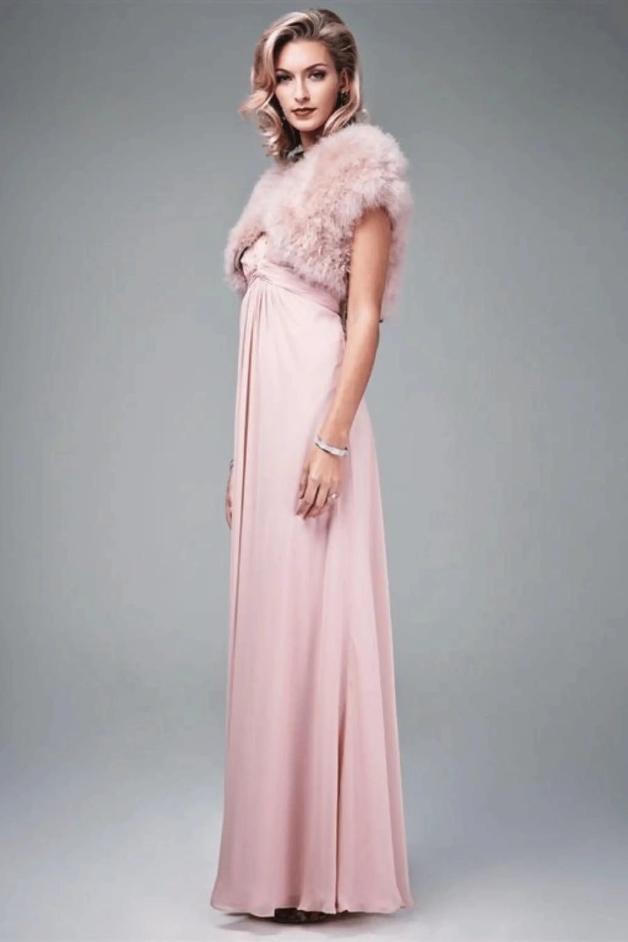 Side view of blush pink Feather Shrug FK042 by Mascara London with a flowing gown, perfect for weddings or elegant parties.