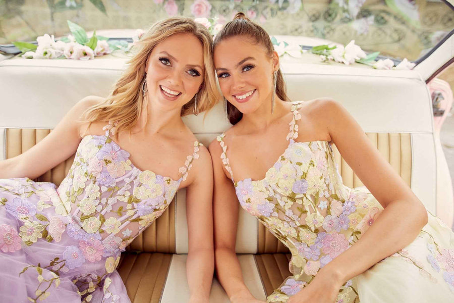 Two women wearing Tiffanys Flora Summer Ballgowns in lilac and yellow, featuring floral bodices ideal for bridesmaids or summer events.