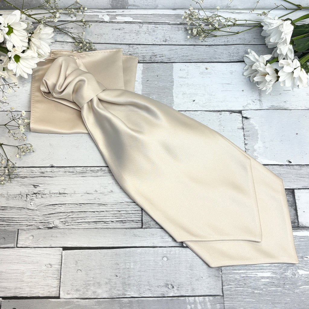 Handmade Antique Champagne Cravat displayed flat on rustic wood with white flowers, showcasing its smooth satin texture and elegant wedding style.