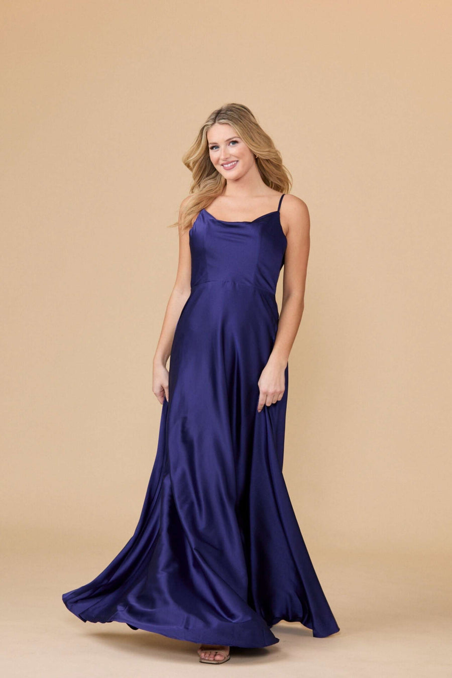 Navy satin gown with cowl neckline and flowing skirt, perfect for prom or evening events. Features adjustable spaghetti straps for a custom fit.