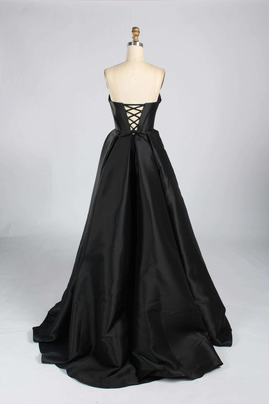 Back view of Jessica Stuart 33313B black satin strapless prom gown with lace-up corset closure and dramatic floor-length skirt.
