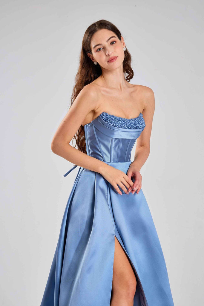 Detail of Steele Blue Pearl Evening Gown’s pearl-embellished neckline and pleated satin skirt with pockets, designed by Jessica Stuart for elegant occasions.