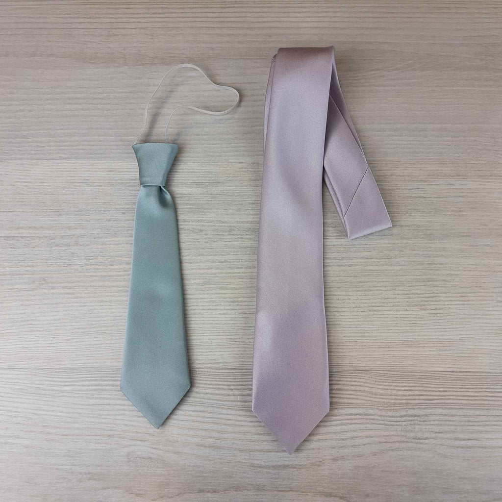 Side-by-side comparison of boys ties: elasticated tie for under 5s and self tie for ages 6-12. Shop plum boys ties in two size options.
