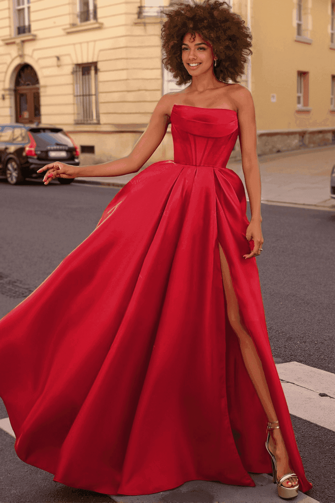 Carmen Ball Gown - Wine Red Satin with Pockets features a strapless bodice, thigh-high slit, and flowing skirt. Ideal for prom or formal events.
