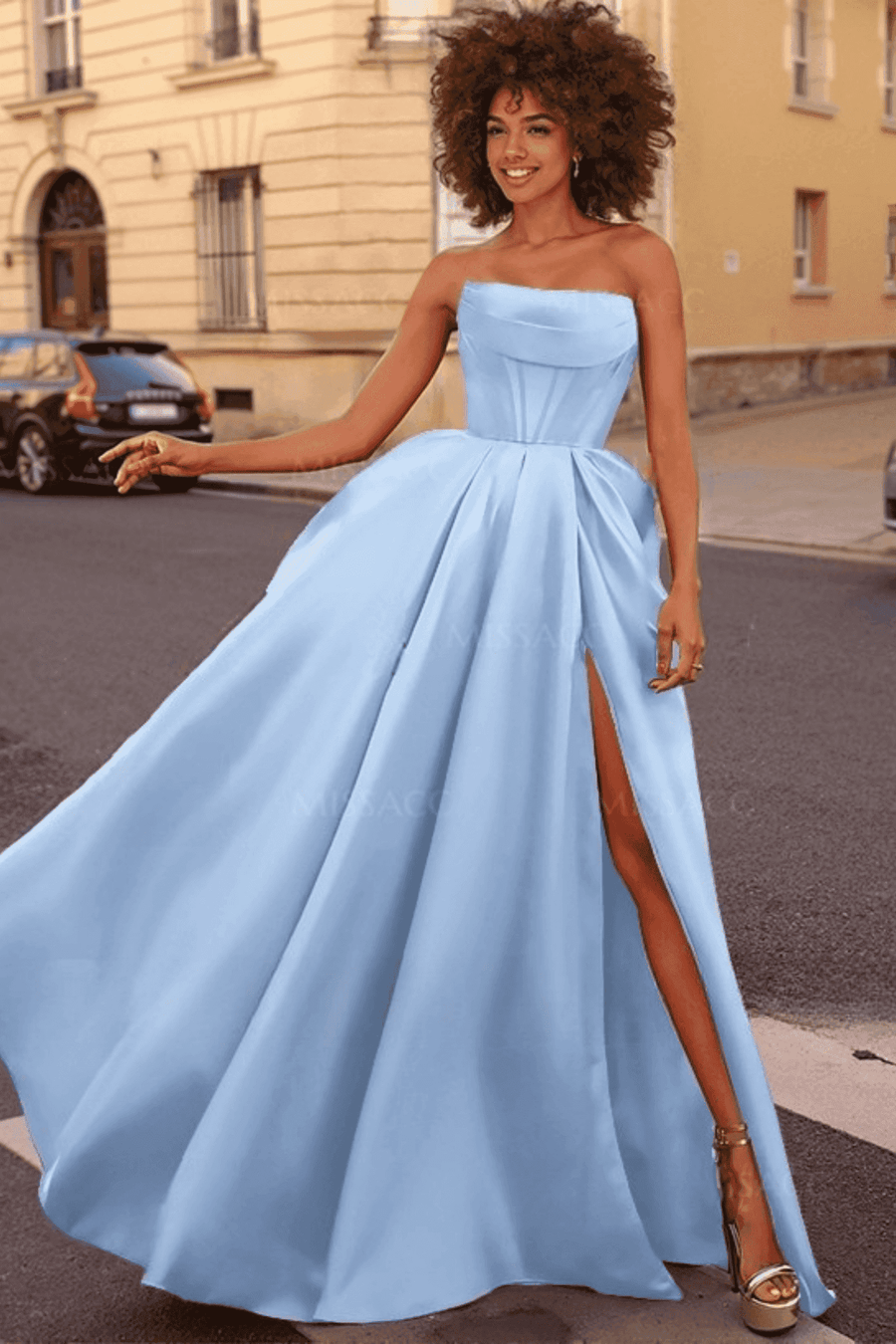 Carmen Ball Gown in light blue satin featuring a strapless neckline, pleated full skirt, thigh-high side slit, and hidden pockets. Ideal for prom or red carpet.
