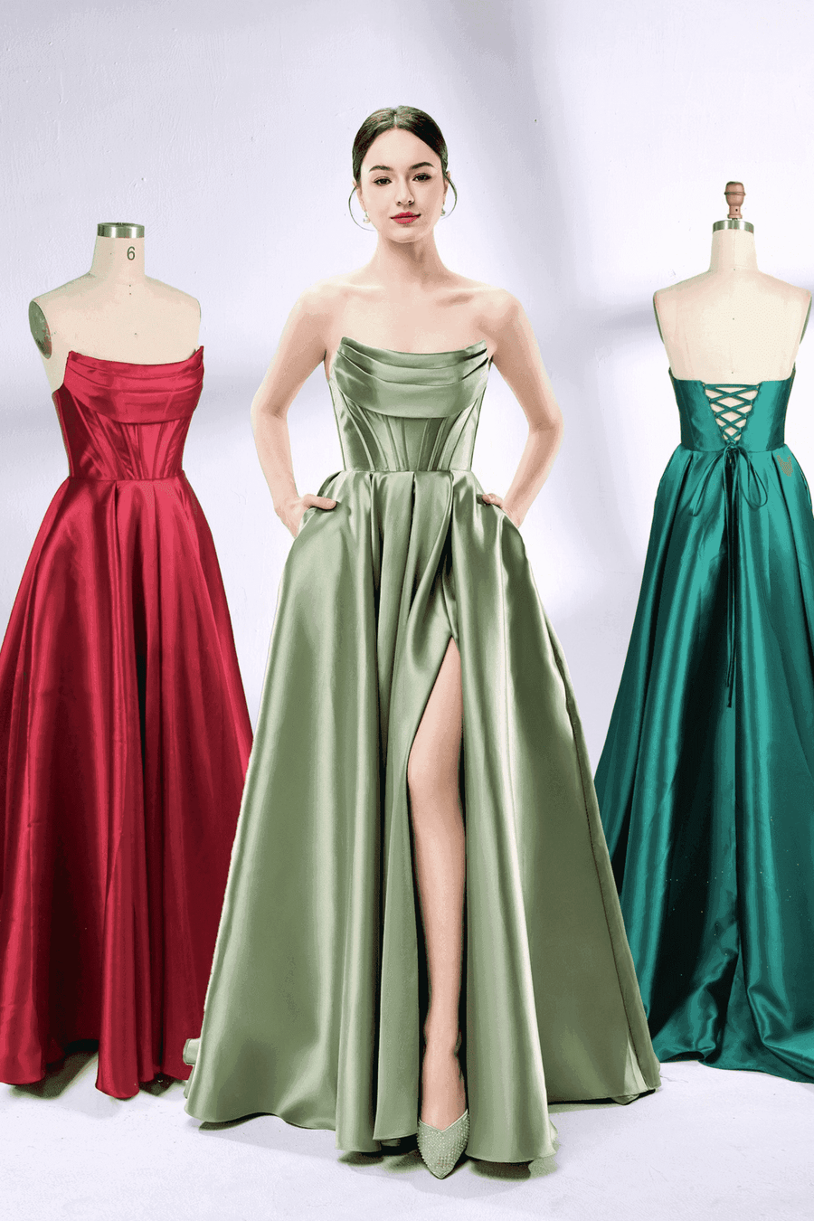 Carmen Ball Gown - Wine Red Satin with Pockets displayed on mannequin, featuring strapless bodice and pleated skirt for prom or formal events.