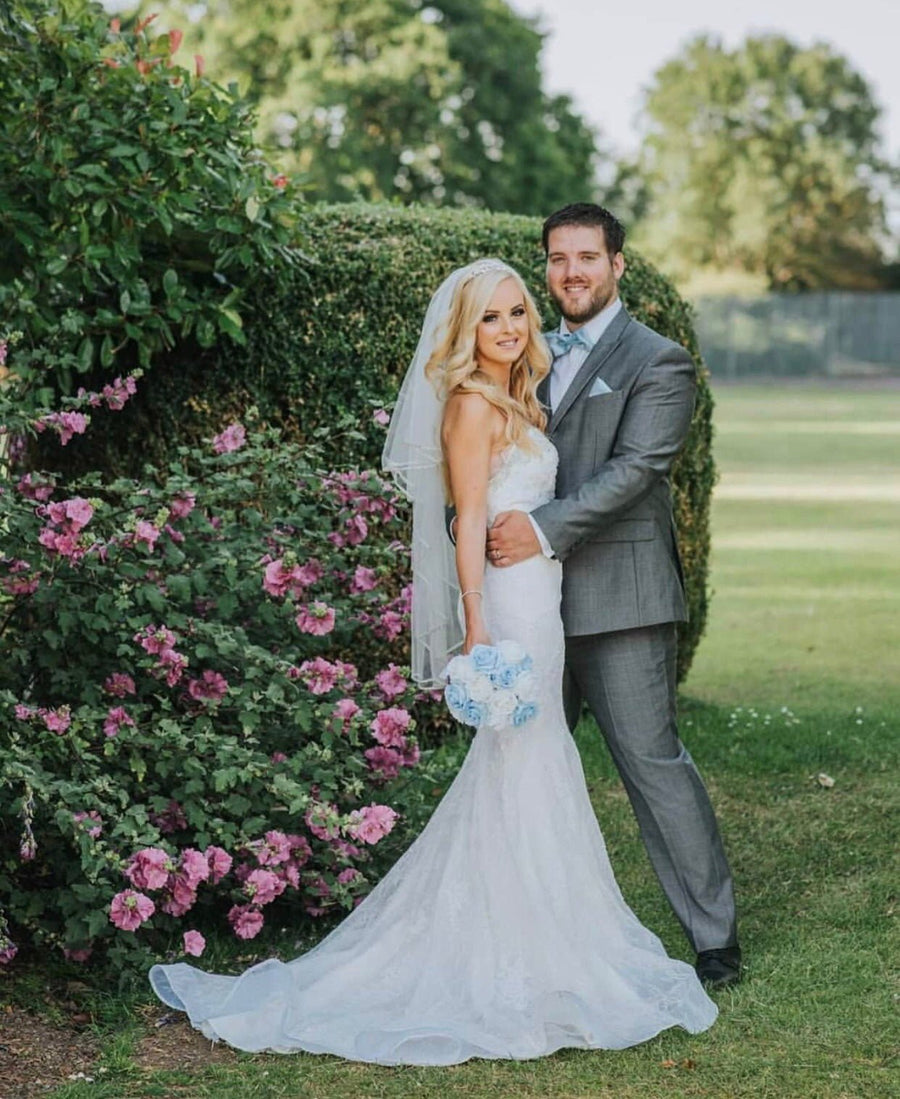 Bride and groom in wedding attire; groom wears grey suit, possibly styled with Light Blue Bow Tie - Wedding Accessory for elegant coordination.