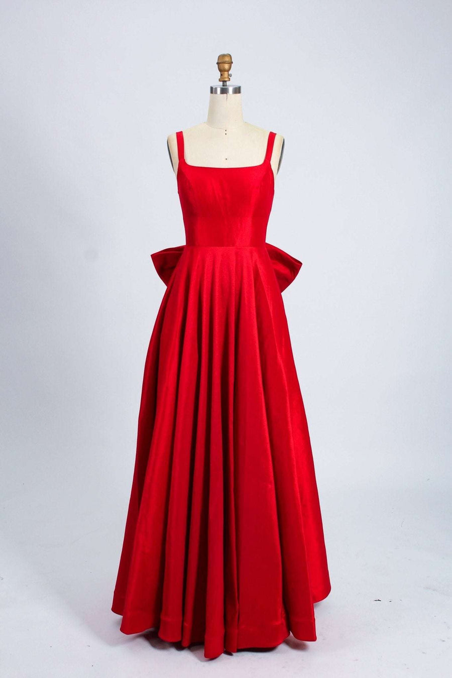 Tillie Red Bow Ball Gown with Pockets by Jessica Stuart featuring a scoop neckline, wide straps, and a dramatic detachable bow at the back.