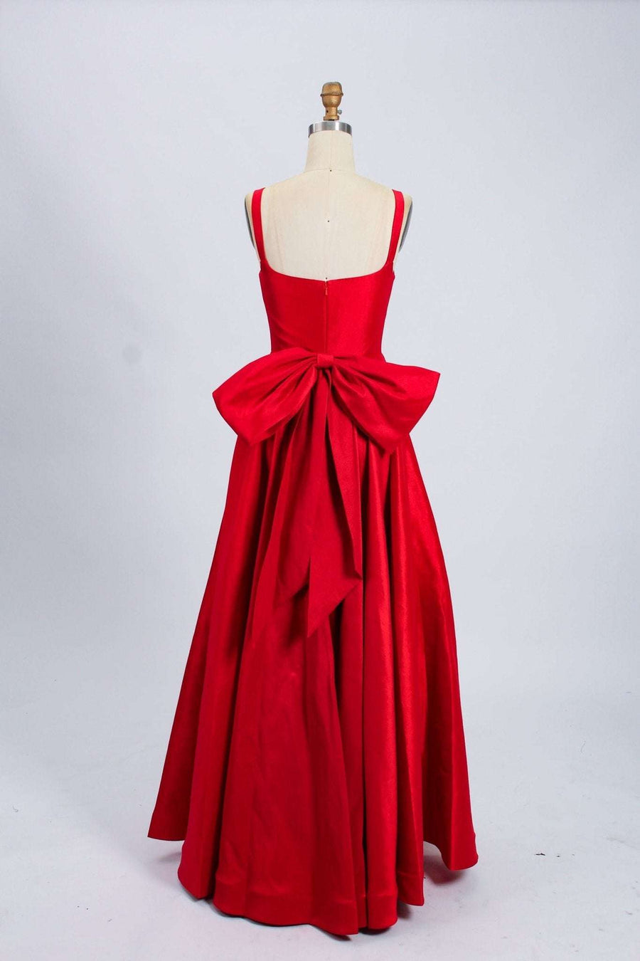 Back view of Tillie Red Bow Ball Gown by Jessica Stuart featuring a dramatic detachable bow and full-length taffeta skirt with hidden pockets.